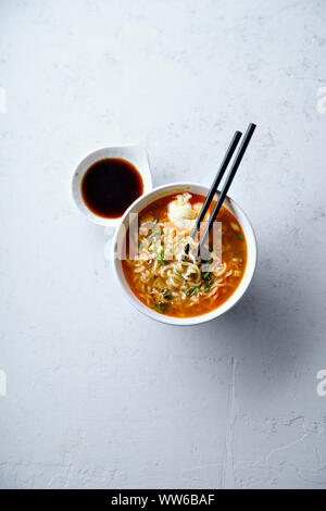 Image de frais généraux avec des nouilles ramen japonais facile, bouillon de porc, l'œuf et le poireau dans un bol blanc sur fond de béton Banque D'Images