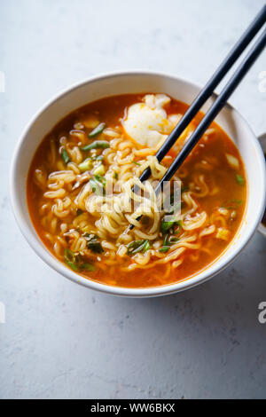 Avec des nouilles ramen japonais facile, bouillon de porc, l'œuf et le poireau dans un bol blanc sur fond de béton Banque D'Images