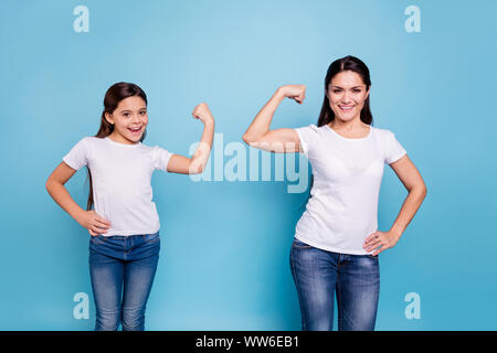 La photo en gros deux personnes brown haired maman maman petite fille main sur le biceps qui dirigent monde filles portent des t-shirts bleu vif isolées Banque D'Images