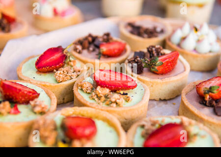 Arrière-plan coloré rempli de gâteaux et desserts aux fruits frais. Un assortiment de différents mini gâteaux à la crème, chocolat et fruits rouges. Banque D'Images