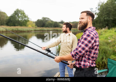 Les amis masculins avec des cannes à pêche sur la jetée du lac Banque D'Images