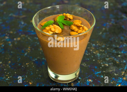 Dessert au chocolat avec des noix dans un verre sur une table en bois. Banque D'Images