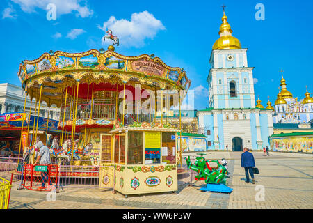 KIEV, UKRAINE - 11 AVRIL 2018 : le carrousel dans un petit parc d'attractions contre le clocher du monastère St Michael Golden Dôme Banque D'Images