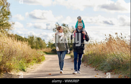 Famille heureuse à marcher le long de la route d'automne Banque D'Images