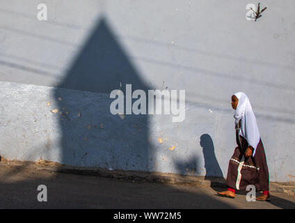 Femme éthiopienne en passant en face de l'ombre d'un minaret mosquée dans la rue, Harari région, Harar, Ethiopie Banque D'Images