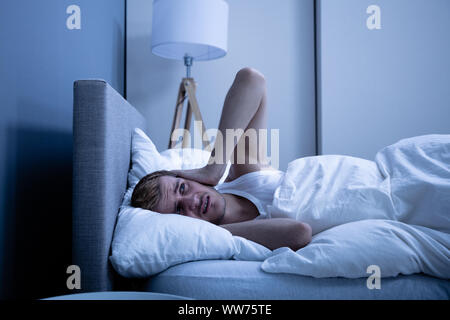 L'homme qui couvre sa tête avec oreiller au lit Banque D'Images