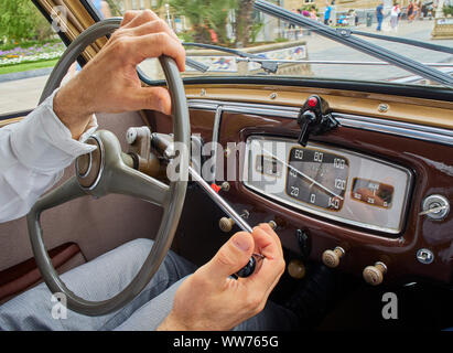 Un homme les mains au volant d'une voiture classique italien. Banque D'Images