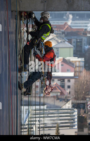 Grimpeur escalade la façade de la tour de chirurgie clinique d'Innsbruck, Tyrol, Autriche Banque D'Images