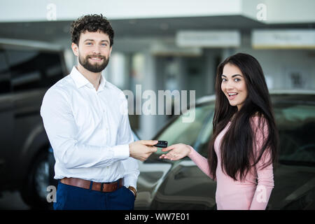 Salesman handing clés de voiture à smiling woman Banque D'Images