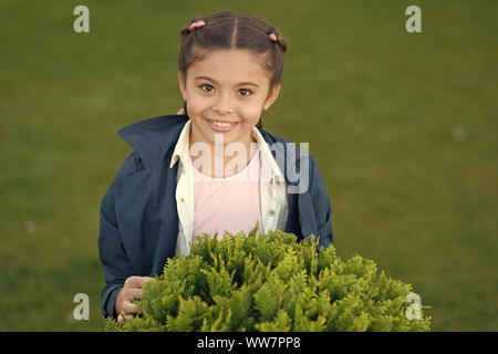 Sourire pur. Sourire honnête de kid en bonne santé. Temps d'automne. La mode printemps pour petite fille. L'extérieur du parc. Heureux l'enfant avec thuja. L'harmonie de la nature. Peu Banque D'Images