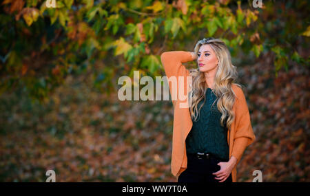 Tenues décontractées confortable pour la fin de l'automne. Création pour agréable fin de semaine. Femme à pied. La lumière au coucher du soleil Tenue confortable. Adorable petite fille blonde posing in outfit chaleureux et cosy de l'automne nature fond flou. Banque D'Images