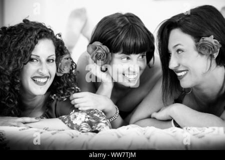 Belles jeunes femmes à la maison d'amis s'étendit sur le lit avec une rose dans les cheveux de rester ensemble avec le bonheur et le plaisir. concept d'amitié pour un groupe de personnes Banque D'Images