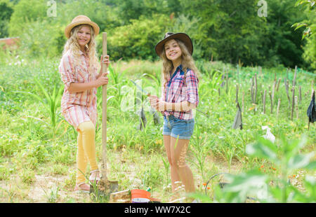 Sœurs ensemble l'aide à l'exploitation agricole. Pour la plantation des plantes. Les enfants travaillant dans les jardin rustique. La plantation et l'arrosage. Planter des légumes. Concept de l'agriculture. La culture de légumes. Espoir pour la récolte de nice. Banque D'Images