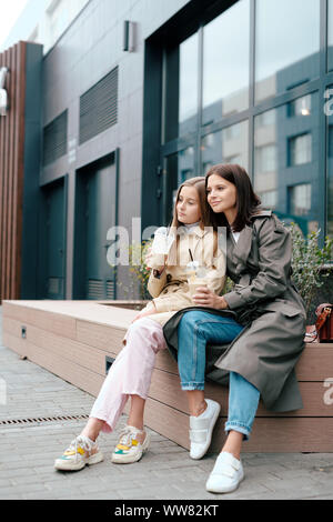 Deux femelles reposant dans smart casual ayant des boissons tout en détente en plein air Banque D'Images