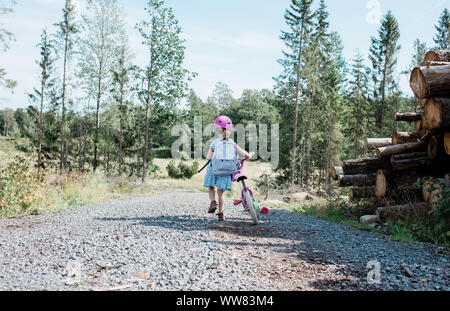 Jeune fille qui marche avec son vélo le long d'un chemin de campagne en été Banque D'Images