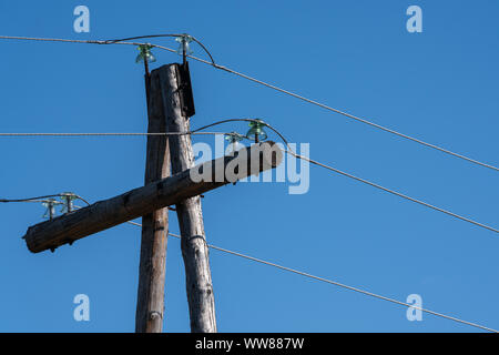 Vieux pylône d'électricité câbles sur poteaux de bois sur fond de ciel bleu en journée ensoleillée Banque D'Images