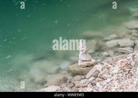 Randonnée d'automne autour de la Pragser Wildsee dans les Dolomites, Italie, cairn sur la rive, gouttes dans l'eau bleu turquoise Banque D'Images