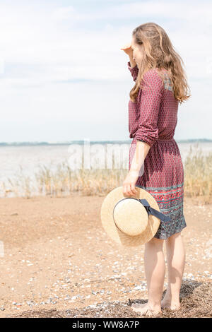 Jeune femme en robe d'été et chapeau de paille sur la côte Banque D'Images