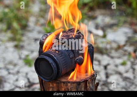 Accident avec la propriété des photographes, en raison de la mauvaise chance fatale, l'appareil photo du perdant incendié lors d'un incendie de forêt. Fondu d'incendie et carbonisée Banque D'Images