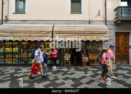 Vue sur la rue de la ville alpine d'aoste avec l'extérieur d'un alcool, vins et produits locaux store et les touristes en été, de la vallée d'Aoste, Alpes, Italie Banque D'Images