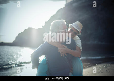 Happy senior couple s'amuser et profiter de l'activité de loisirs de plein air sur la plage. l'homme porter la femme sur le dos pour profiter ensemble d'un mode de vie à la retraite à la plage Banque D'Images