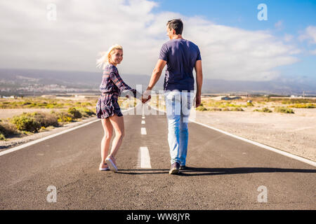 Joli couple en relation en tenant les mains et marcher ensemble sur un long chemin route tout droit vers l'avenir. vie pour toujours dans la coulée et de la famille dans l'amour concept. beau paysage et lieu désert Banque D'Images