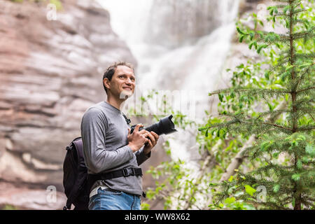 Le ruisseau Hays cascade de Redstone, Colorado au cours de l'été avec l'homme debout, photographe avec appareil photo happy smiling Banque D'Images