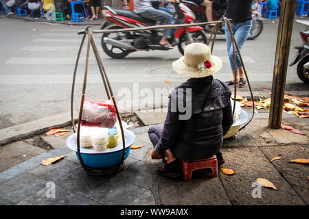 Éditorial. Une femme vietnamienne vendant de la nourriture de rue sur le côté de la rue animée dans le quartier français de Hanoi ville, Vietnam Banque D'Images