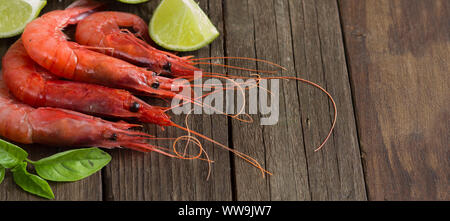 Crevettes crues avec de la chaux et des herbes sur fond sombre Banque D'Images