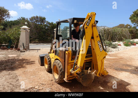 Algarve, Portugal 10 Avril 2019 : UN JCB mini digger utilisée pour faire le travail d'aménagement paysager dans un jardin de devant Banque D'Images