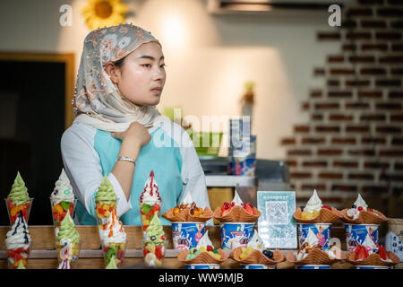 Xian, Chine - Juillet 2019 : femme musulmane vend de la crème glacée comme dessert avec des morceaux de fruits frais à la vente sur l'alimentation de rue dans le quartier musulman Banque D'Images