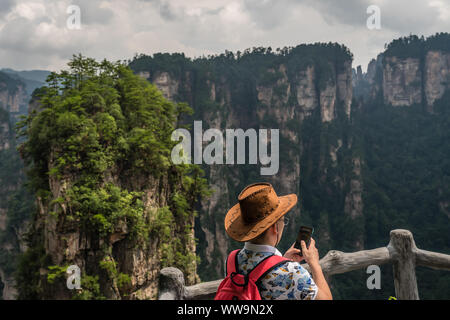 Zhangjiajie, Chine - Août 2019 : les touristes à admirer la vue et prendre des photos sur le smartphone sur le pilier du pont de vue du ciel, Avatar moun Banque D'Images