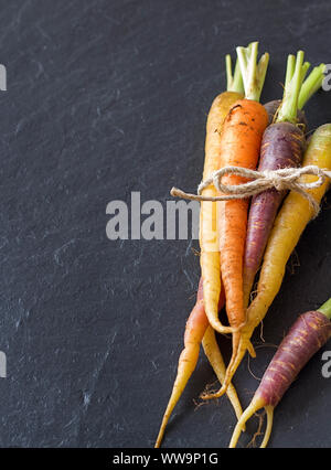 Groupe de produits frais bio carottes arc-en-ciel sur un fond sombre Banque D'Images