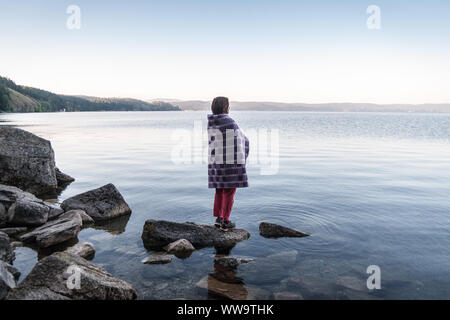 La méditation sur la côte du lac au lever du soleil Banque D'Images