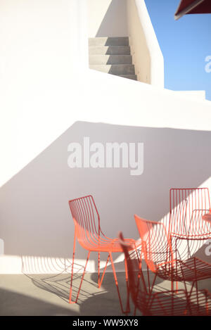 Santorin, Grèce - 23 juin 2018 : Début de la lumière du matin sur des chaises en métal rouge et un blanc et gris escalier dans Santorini. Banque D'Images