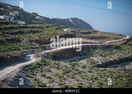 Santorin, Grèce - 23 juin 2018 : Début de la lumière du matin sur une route de terre et de maisons sur une colline dans la région de Pygros de Santorin. Banque D'Images