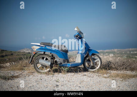 Santorin, Grèce - 23 juin 2018 : un vieux scooter bleu est située sur une colline dans le quartier Pygros à Santorin en été. Banque D'Images