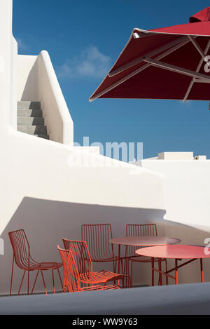 Santorin, Grèce - 23 juin 2018 : tables et chaises rouge sous un parapluie rouge dans le quartier Pygros à Santorin en été. Banque D'Images