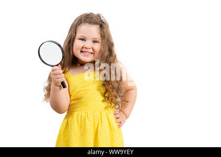 Peu preschool girl holding magnifier et souriant sur fond blanc. Banque D'Images