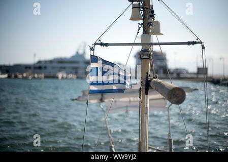 Naxo, Grèce - 26 juin 2018 : un drapeau grec vagues dans le vent à bord d'un navire dans le Port de Naxos. Banque D'Images