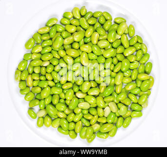 Edamame. Le soja vert sur une assiette blanche. Mukimame non mûres, les graines de soja à l'extérieur de la gousse. Glycine max, une légumineuse, comestibles après cuisson et source de protéines. Banque D'Images