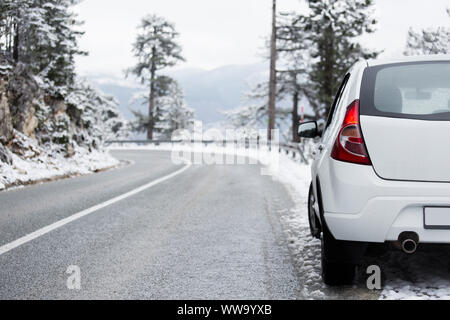 Voiture blanche sur une route d'hiver par une forêt couverte de neige. Vue de côté Banque D'Images