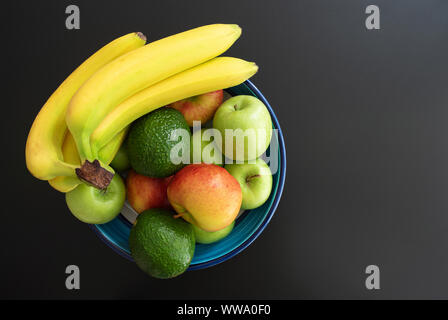 Vue de dessus de la poterie bol rempli de fruits biologiques sains sur fond sombre Banque D'Images