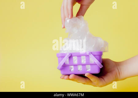 Sacs en polyéthylène dans la main dans le panier sur fond jaune Banque D'Images