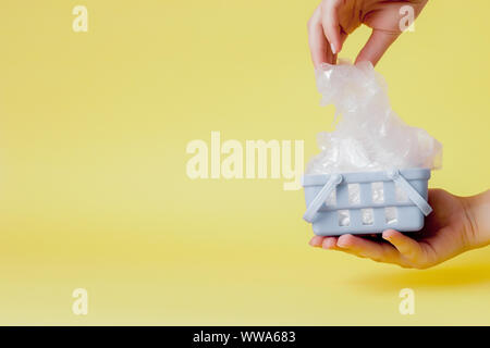 Sacs en polyéthylène dans la main dans le panier sur fond jaune Banque D'Images