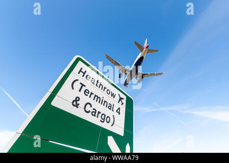 Avion de ligne à réaction British Airways atterrissant à l'aéroport de Londres Heathrow à Hounslow, Londres, Royaume-Uni au-dessus du panneau routier pour le terminal 4 et le fret Banque D'Images