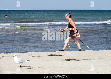 Femme senior marche nordique le long de la plage Mer Baltique Allemagne mode de vie sain vieillissement plage marche femme senior active vive marche Banque D'Images