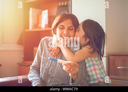 Profitant de la mère avec sa fille tout en regardant le test de grossesse positif Banque D'Images