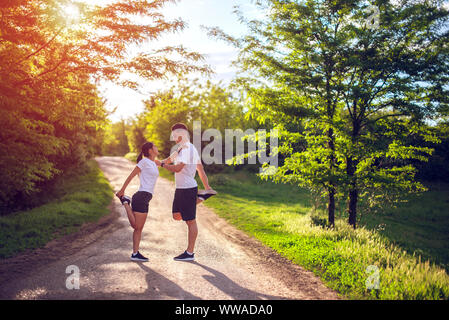 Jeune couple s'étend les jambes sur une route dans le parc Banque D'Images