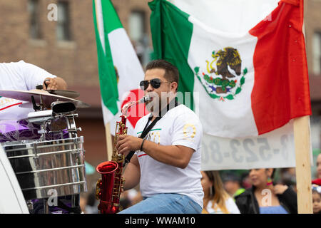 Chicago, Illinois, USA - 8 septembre 2019 - 26th Street Parade de l'indépendance du Mexique, l'homme jouant du saxophone, avec le drapeau mexicain dans son dos le duri Banque D'Images